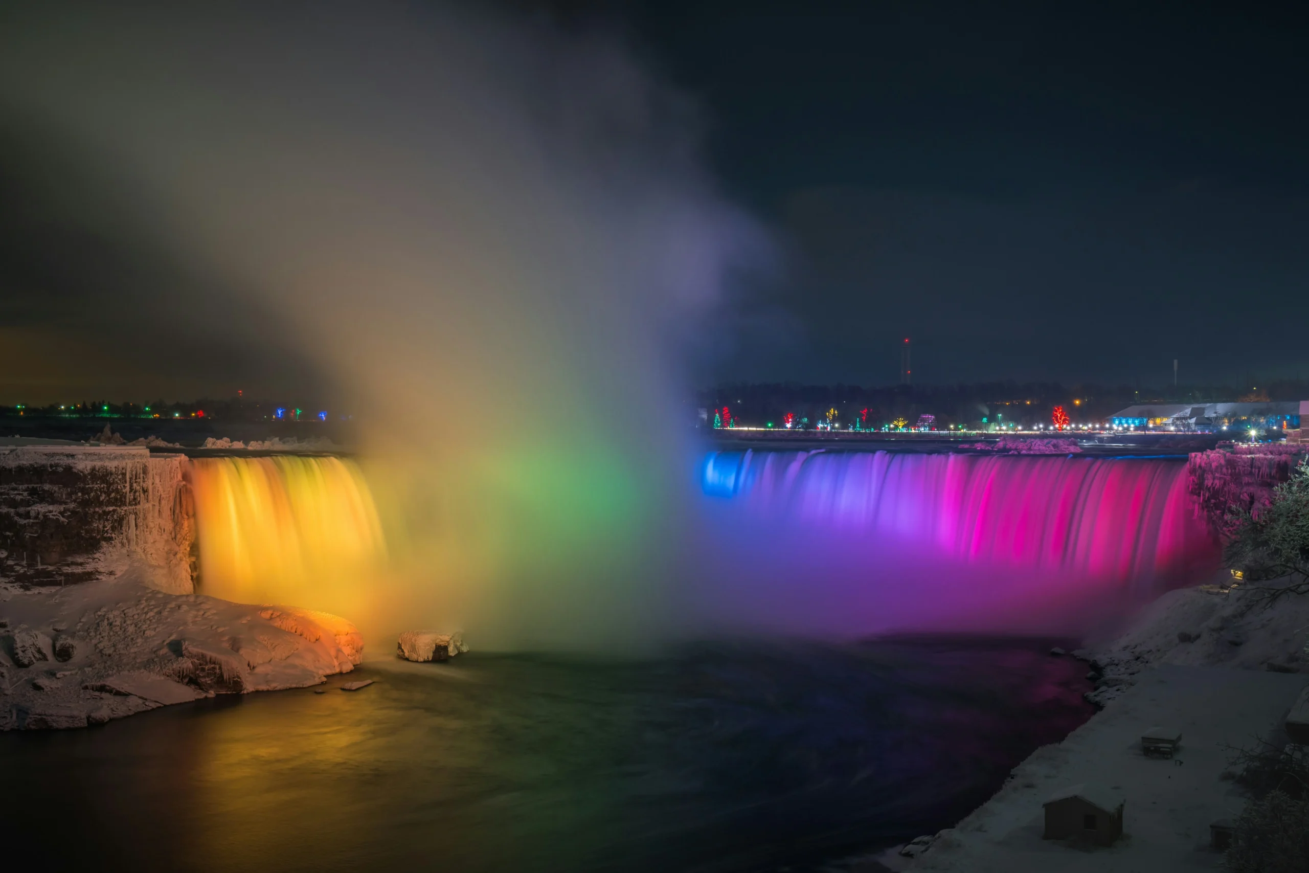Niagara Falls illuminated with colorful lights during winter at night